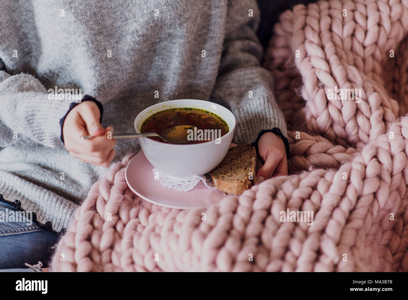 Junge Frau sitzt auf einem Sofa und Essen eine Suppe, detail, Stockfoto