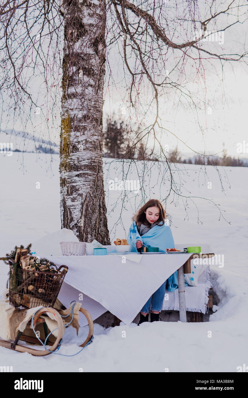 Winter, junge Frau in eine Decke eingewickelt außerhalb isst Stockfoto