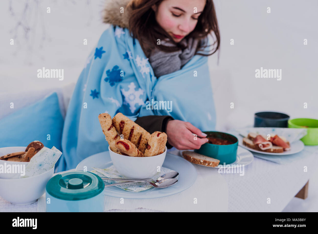 Winter, junge Frau in eine Decke eingewickelt außerhalb isst Stockfoto