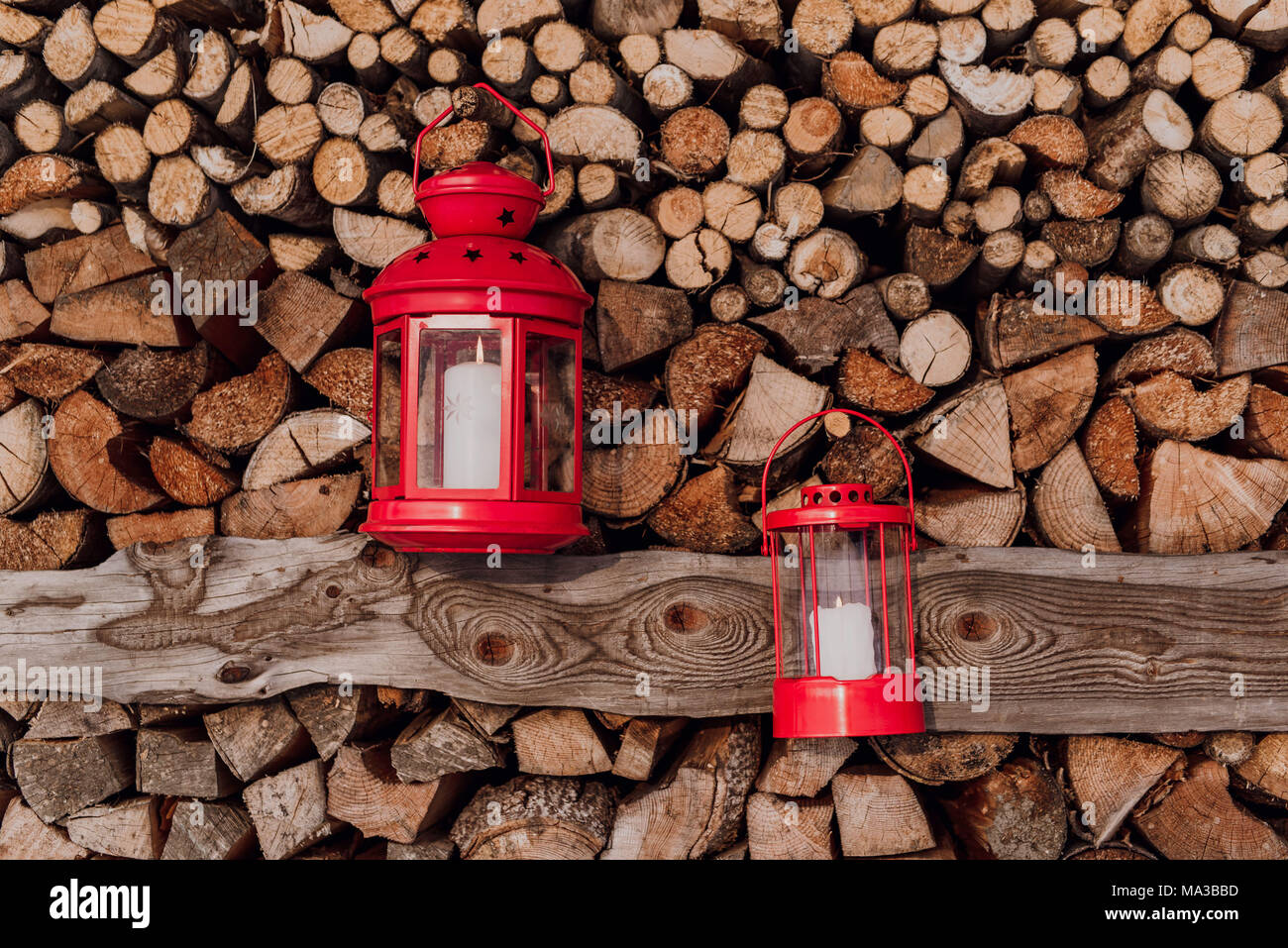 Zwei rote Laternen vor Aufgehäuften brennholz Stockfoto