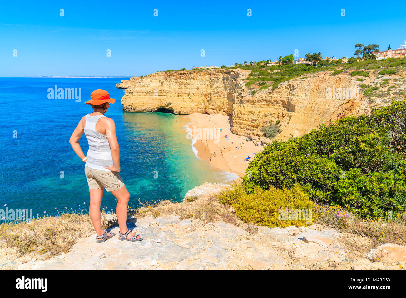 Junge Frau Touristen stehen auf Felsen und mit Blick auf den schönen Strand in der Nähe von Carvoeiro Stadt, Region Algarve, Portugal Stockfoto