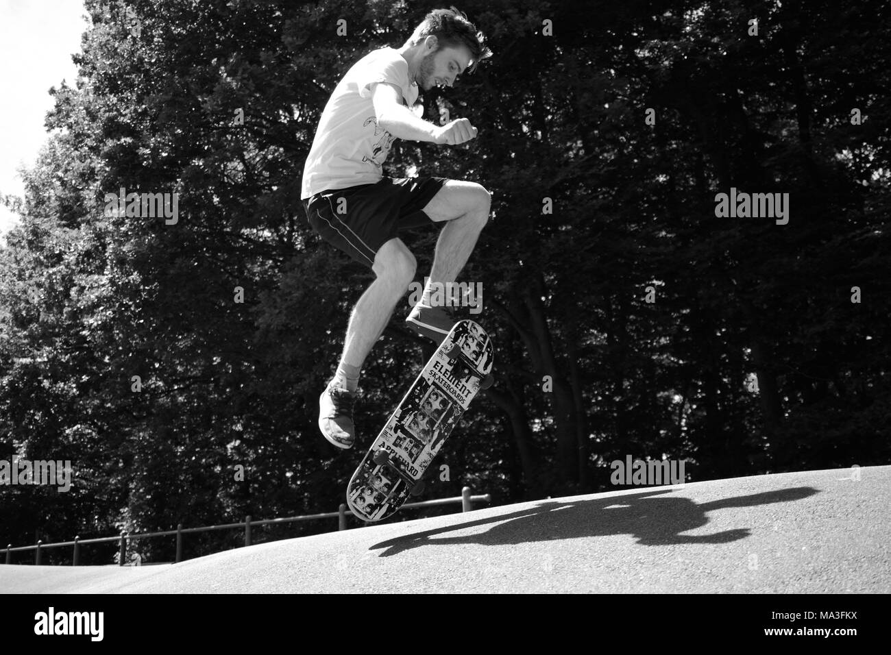 Junger Mann springt mit seinem Skateboard Stockfoto