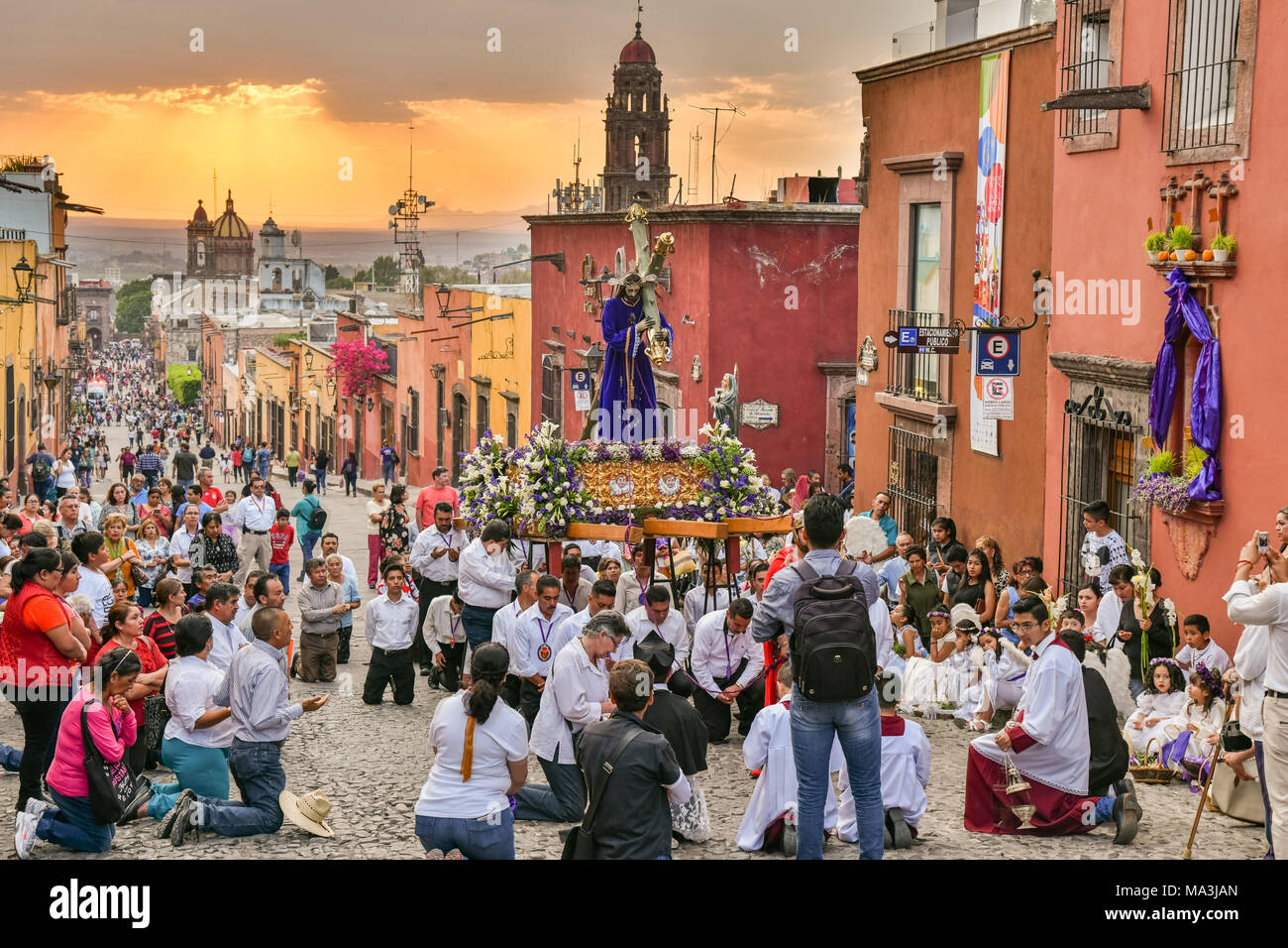 Die katholischen Gläubigen Knien im Gebet während der las Cruzes del Señor Golpe Prozession durch die Straßen bei Sonnenuntergang als Teil der Heiligen Woche März 28, 2018 in San Miguel de Allende, Mexiko. Die Veranstaltung ist Erholung der Passion Jesu Christi auf seinem Weg nach Golgatha für Kreuzigung. Stockfoto