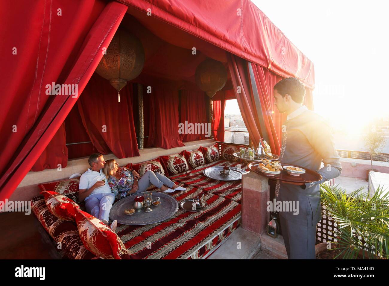 Ein paar und ein Kellner auf der Dachterrasse des Riad AnaYela Hotels (Marrakesch, Marokko) Stockfoto