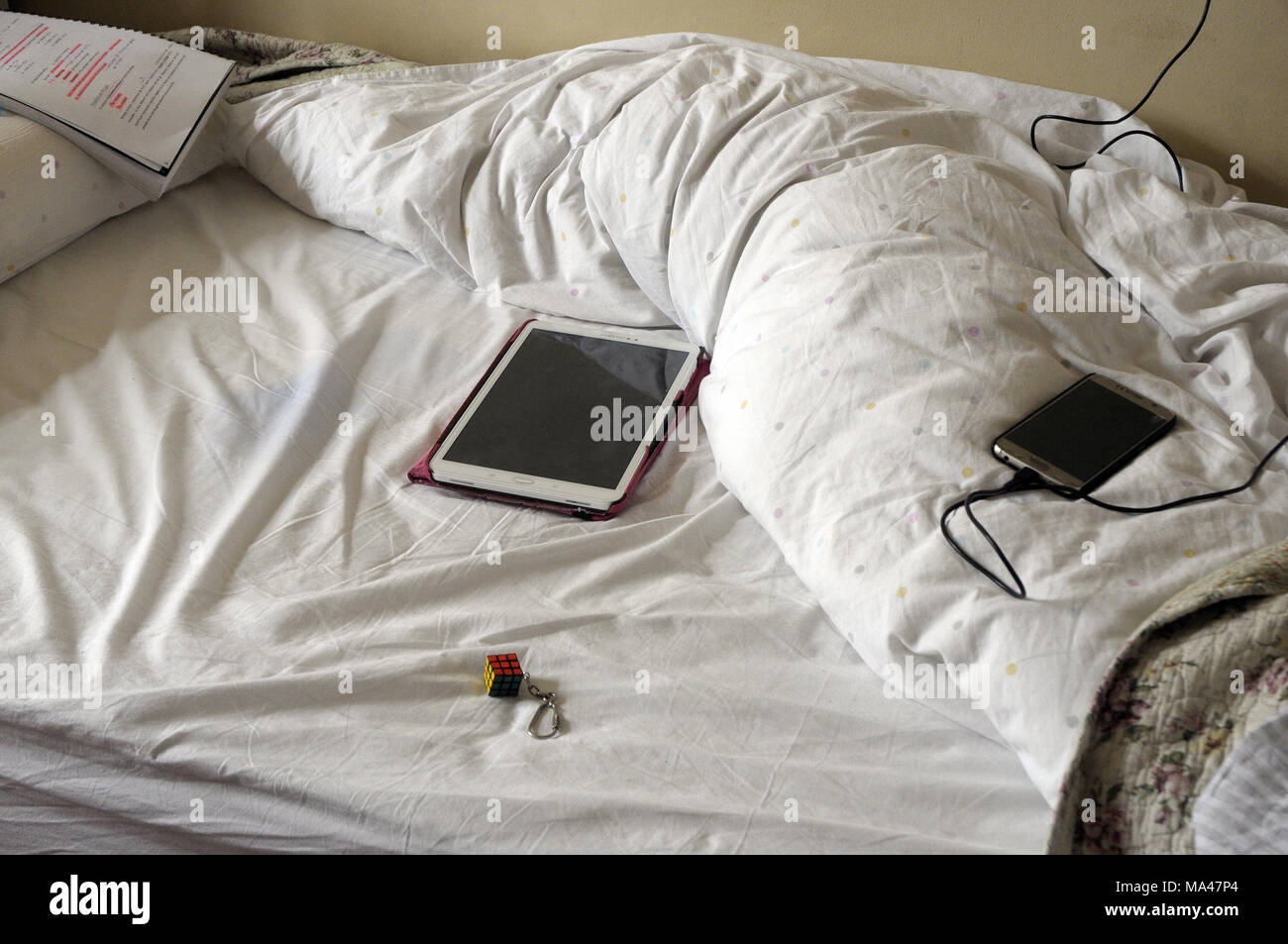 Bett mit Tablet, mobile und rubik s Cube, Stockfoto