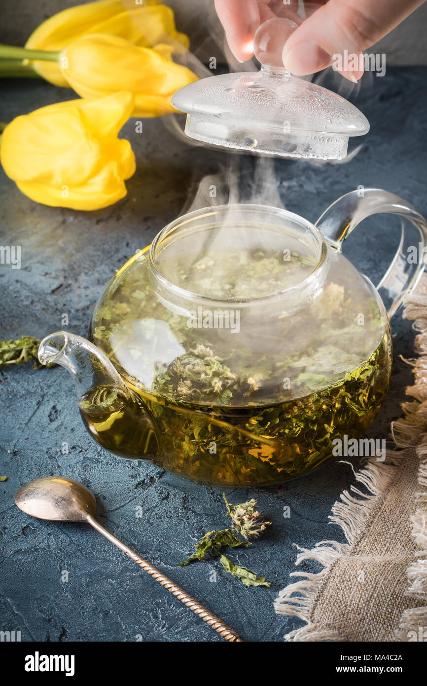 Hand öffnen Deckel der Wasserkocher mit Tee aus Pfefferminze heißes Wasser  fällt Kondensat wird Dampf Teekanne mit detox Trinken auf grauem Stein bac  steigen Stockfotografie - Alamy