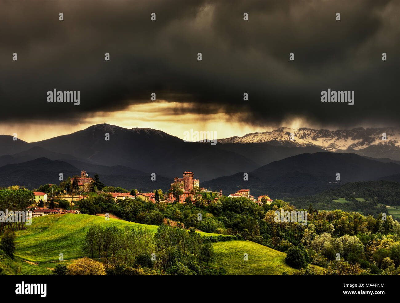 Das Dorf Ciglié mit seiner mittelalterlichen Burg, in den Langhe, Piemont, Italty. Im Hintergrund der Seealpen und den Berg Mindino. Stockfoto