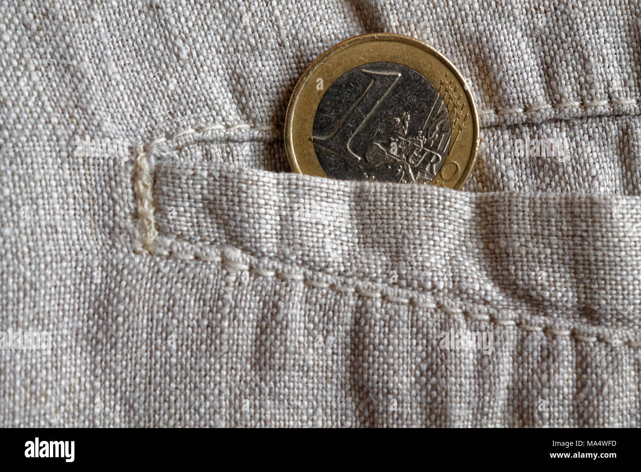 Euro Münze mit einer Stückelung von 1,- Euro in der Hosentasche getragen Leinen Hose Stockfoto