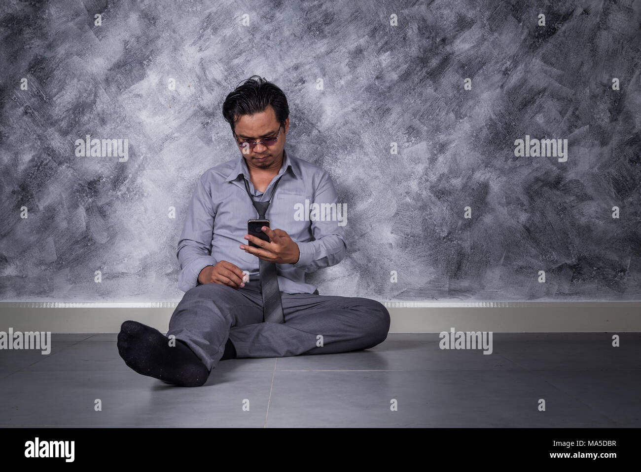Junge gedrückt Geschäftsmann mit Mobiltelefon und sitzen auf dem Boden Stockfoto