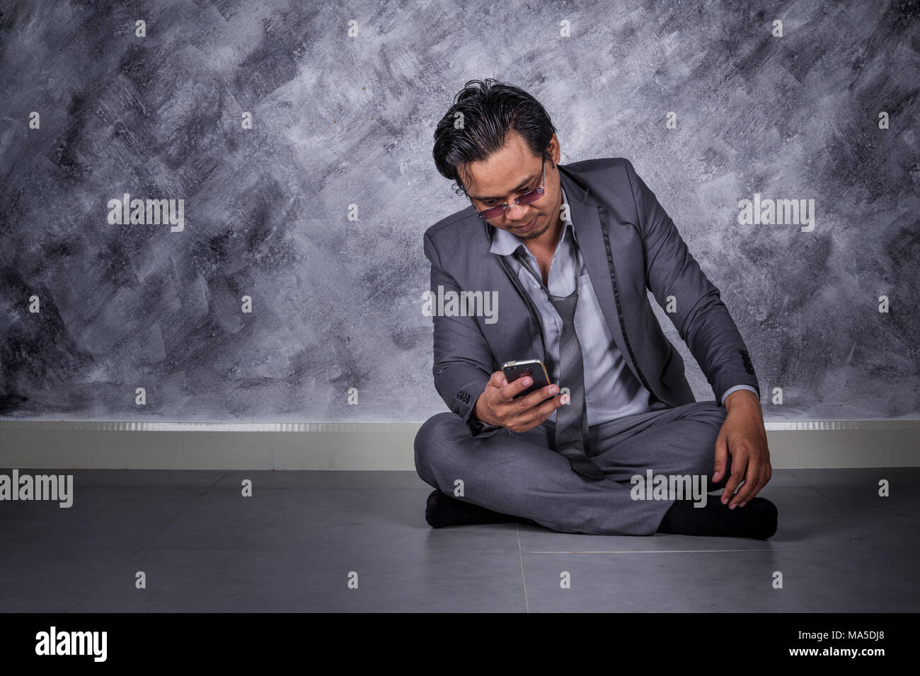 Junge gedrückt Geschäftsmann mit Mobiltelefon und sitzen auf dem Boden Stockfoto