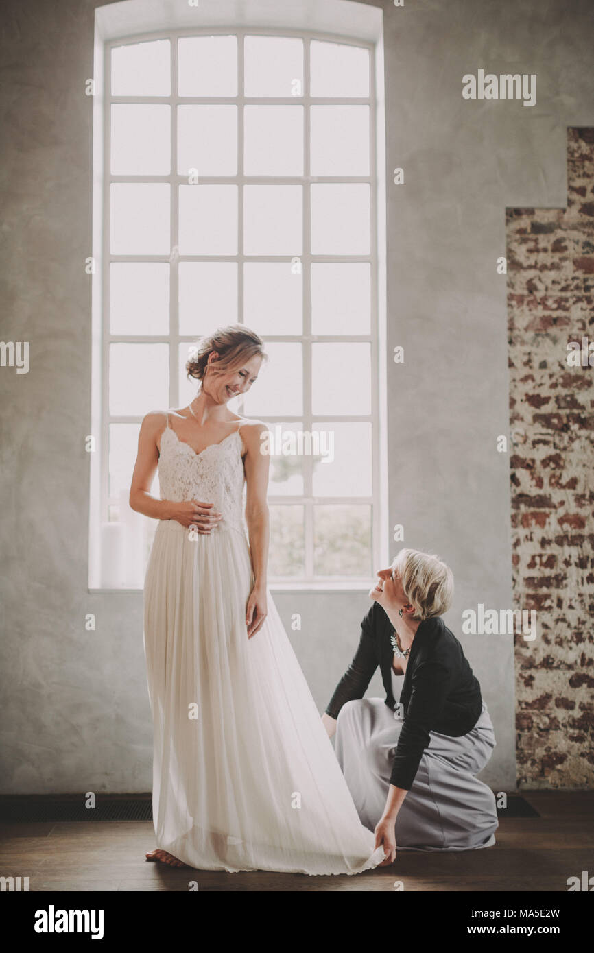 Braut, die versuchen, auf ihr Kleid, Schneiderin Stockfoto