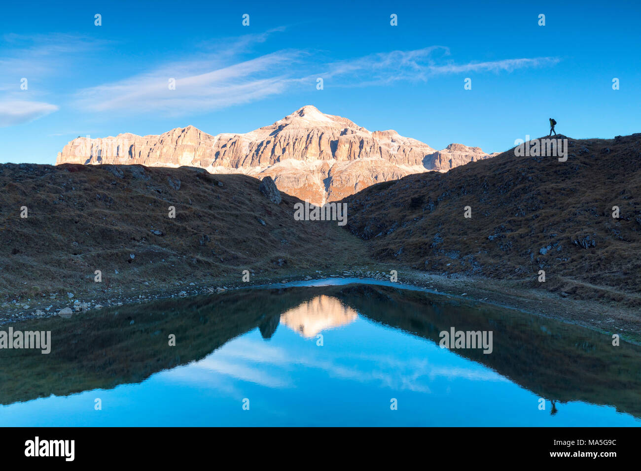 Wanderer in Silhouette in der Nähe einen kleinen Teich mit Sella Gruppe mit der höchsten Piz Boè Berg reflektiert, Pordoijoch, Arabba, Beuuno, Venetien, Italien Stockfoto