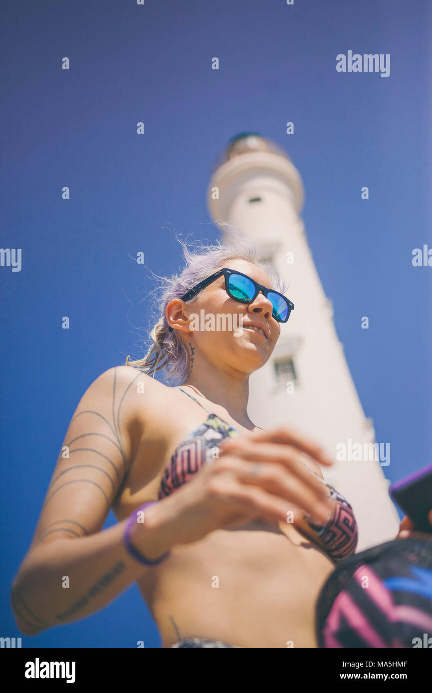 Junge touristische Mädchen mit Sonnenbrille in der Nähe ein Leuchtturm in einem Bikini Stockfoto