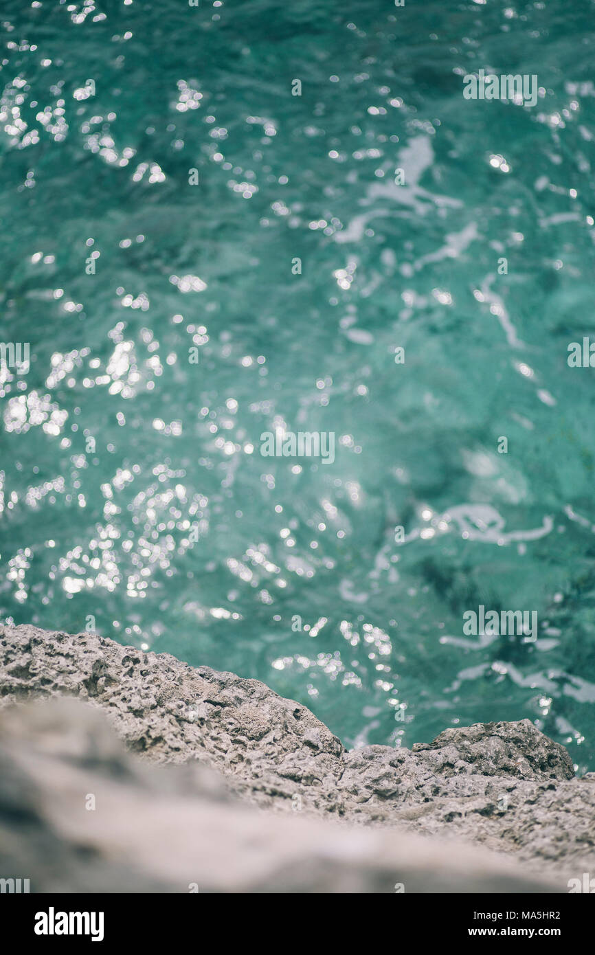 Blaue Meer sprudelnde unter dem grauen harten Steine Stockfoto
