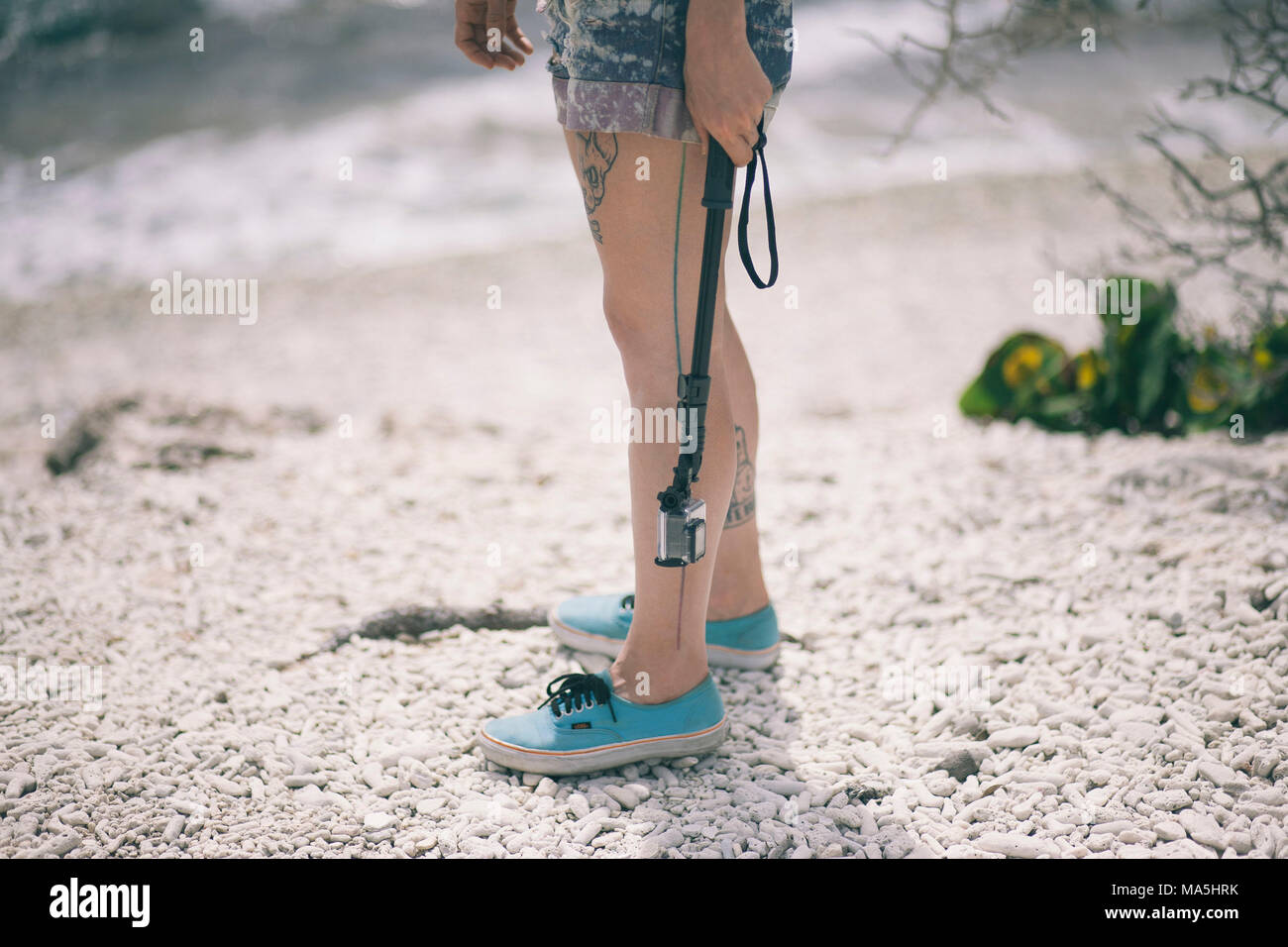 Touristische tätowierte Mädchen hängen eine Unterwasserfauna zufriedenstellend GoPro am Strand mit shorts und Tennis Schuhe Stockfoto
