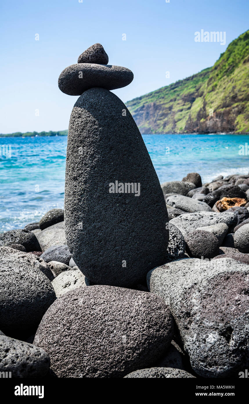 Ein Felsen Cairn auf einem felsigen Strand mit Kealakekua Bay im Hintergrund und Captain Cook Memorial auf der gegenüberliegenden Seite der Bucht. California, South Kona. Stockfoto