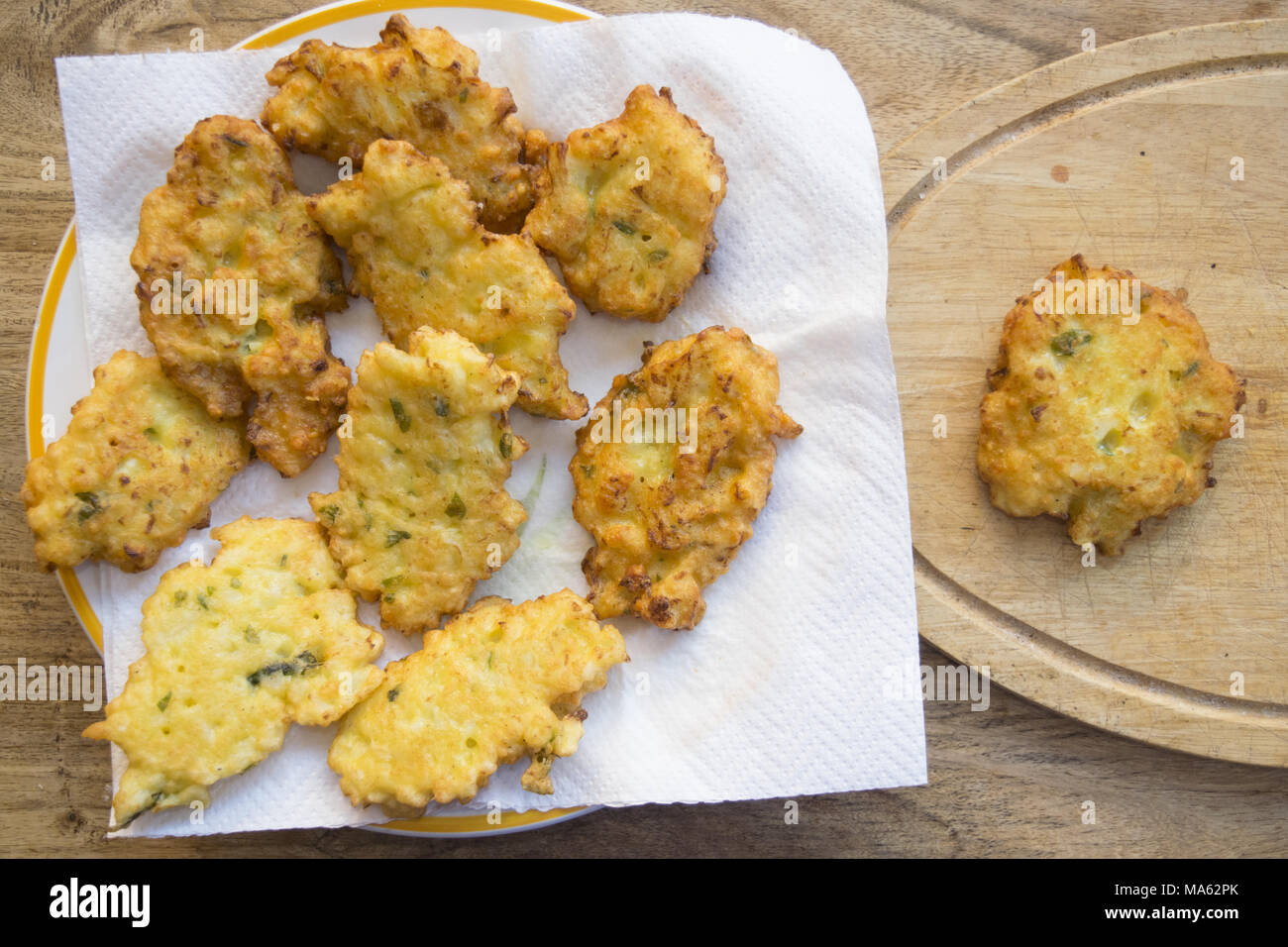 Einzigen gebratenen Mais verzetteln in der Nähe von einem Teller voll von der gleichen Frische Krapfen Stockfoto