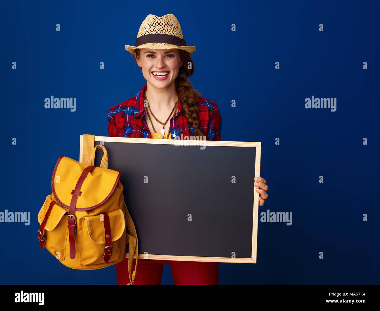 Auf der Suche nach inspirierenden Orten. glückliche junge Frau Wanderer in einen Plaid Shirt, Blank Board auf blauem Hintergrund Stockfoto