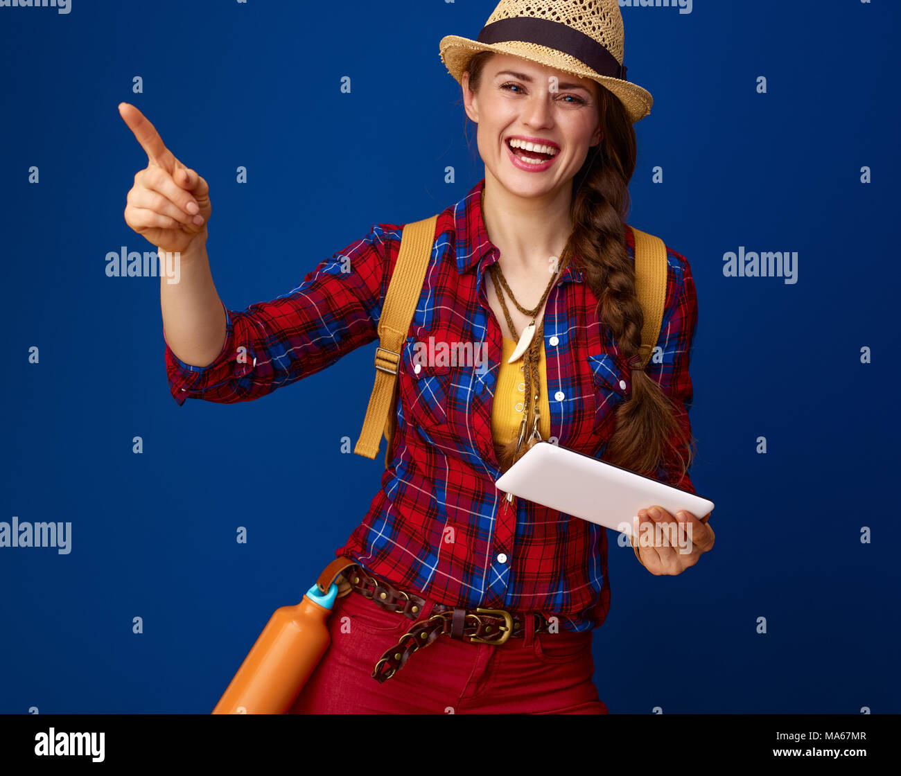 Auf der Suche nach inspirierenden Orten. glückliche junge Frau Wanderer in einen Plaid Shirt mit Tablet-PC auf etwas auf blauem Hintergrund Stockfoto