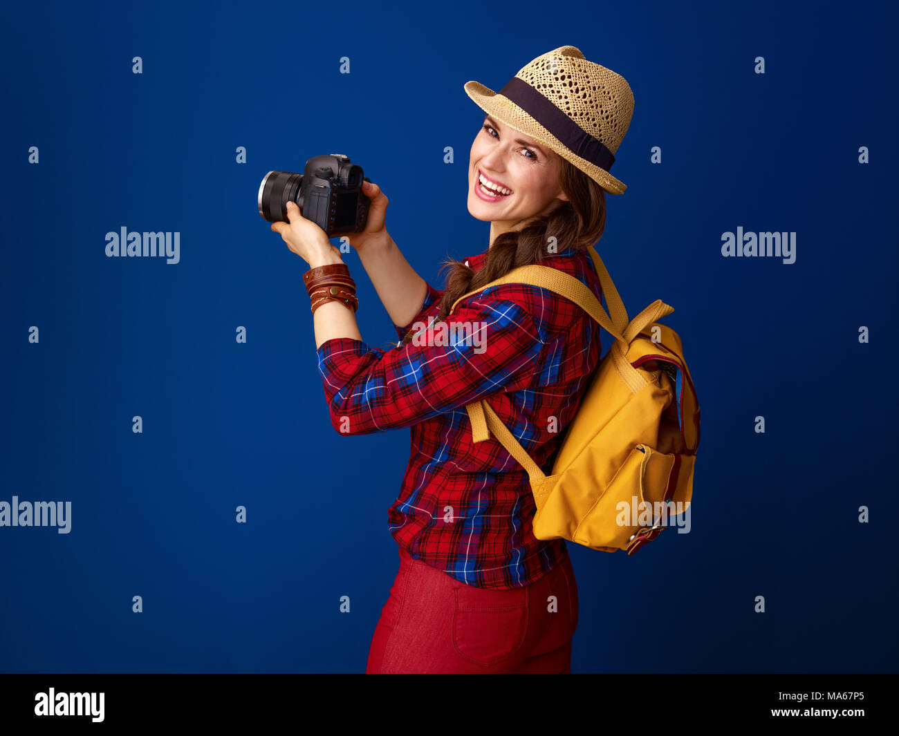 Auf der Suche nach inspirierenden Orten. lächelnden jungen Frau Wanderer in einen Plaid Shirt mit modernen DSLR-Kamera, Foto vor blauem Hintergrund Stockfoto