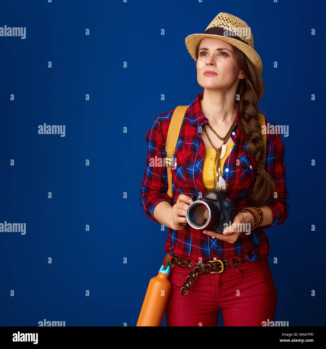 Auf der Suche nach inspirierenden Orten. Junge stolz Frau Wanderer mit Rucksack und Kamera vor blauem Hintergrund Stockfoto