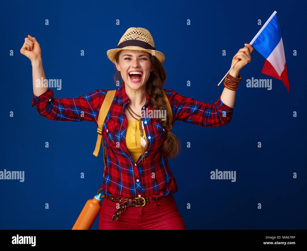 Auf der Suche nach inspirierenden Orten. lächelnden jungen Frau Wanderer in einen Plaid Shirt freuen, die die Flagge Frankreichs isoliert auf Blau Stockfoto