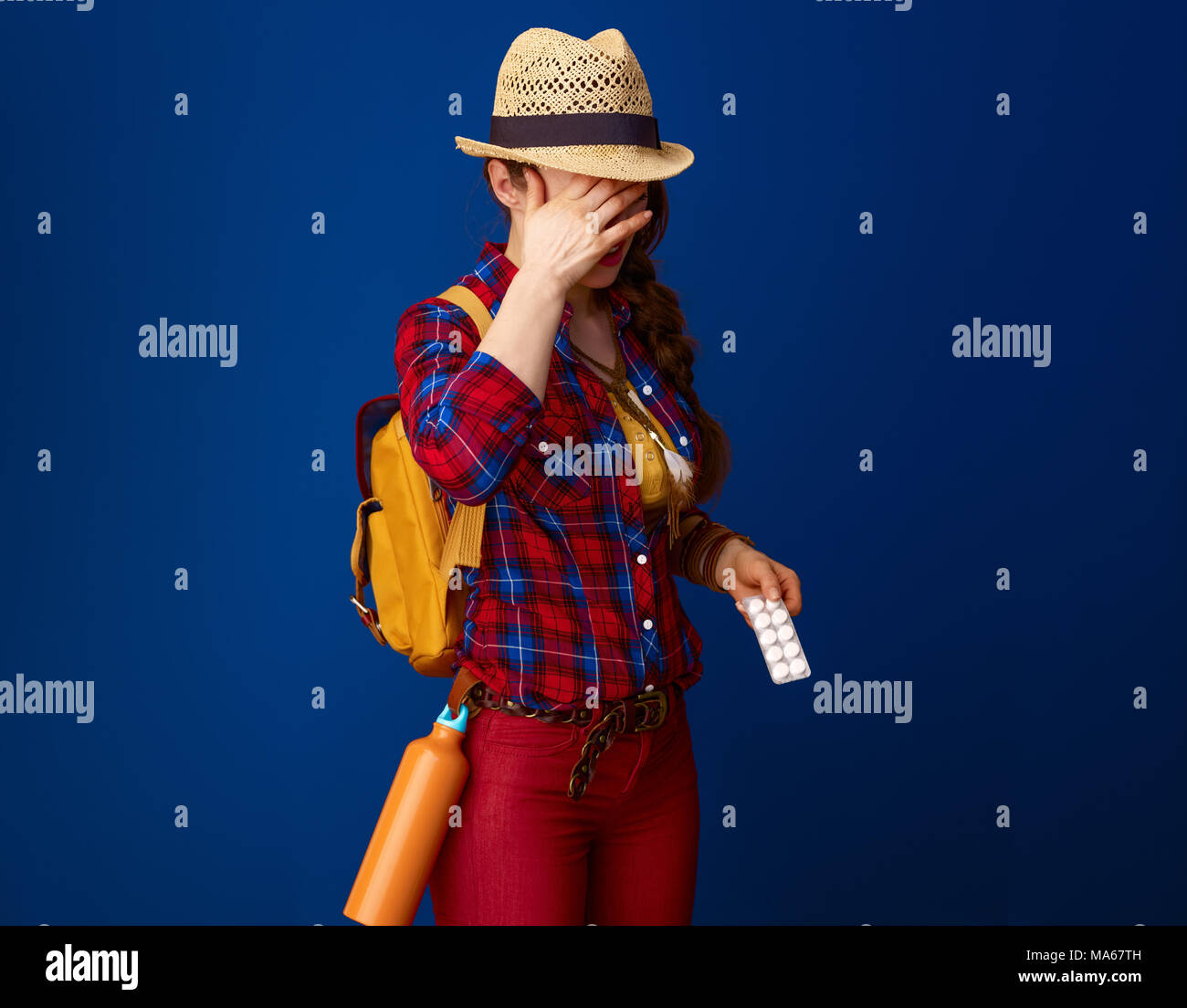 Auf der Suche nach inspirierenden Orten. kranke Frau Wanderer mit Rucksack mit Pillen in einer Blisterpackung Schmerzen auf blauem Hintergrund Stockfoto