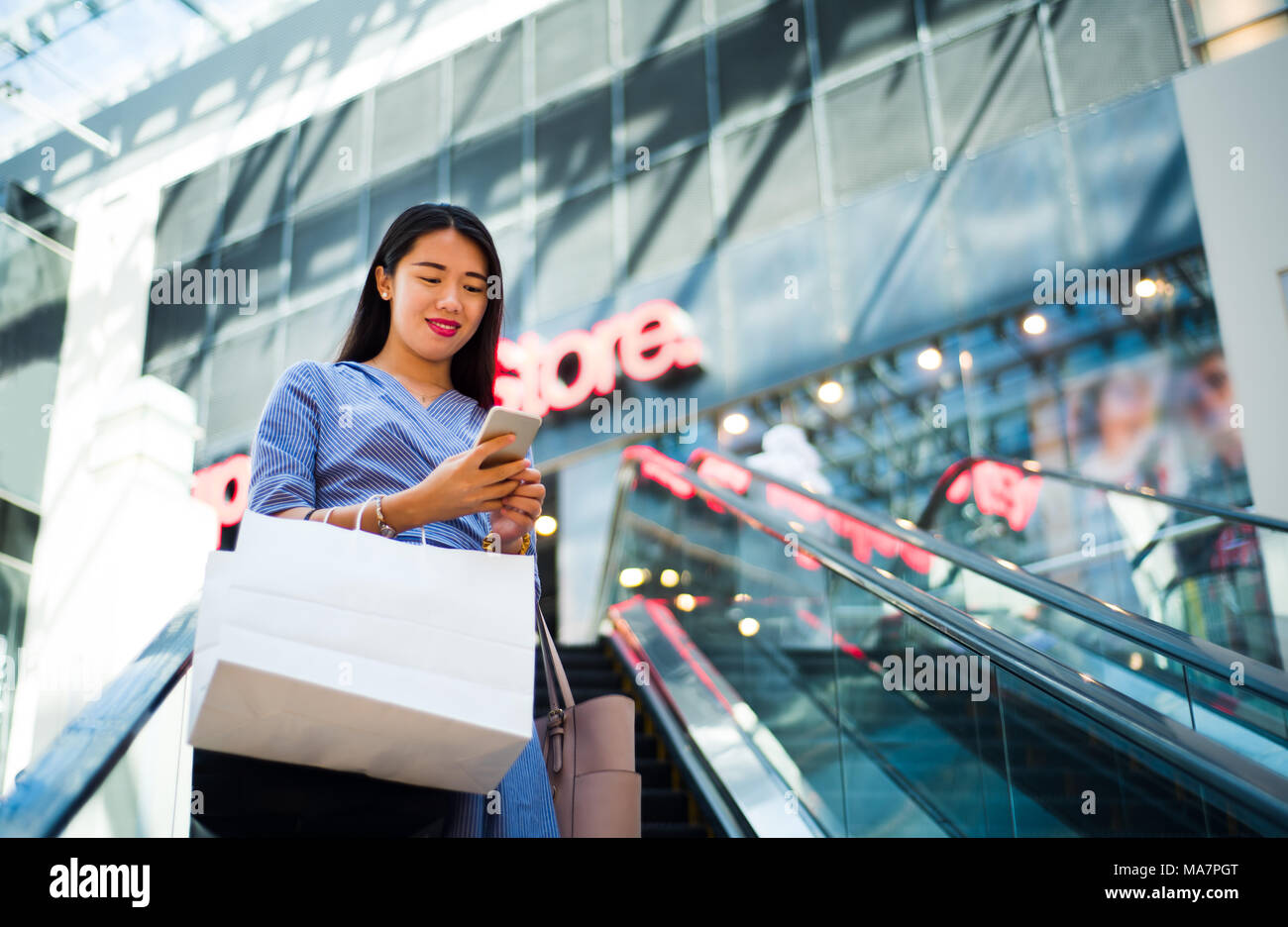Mädchen mit Telefon, während auf Rolltreppen in der Mall Stockfoto