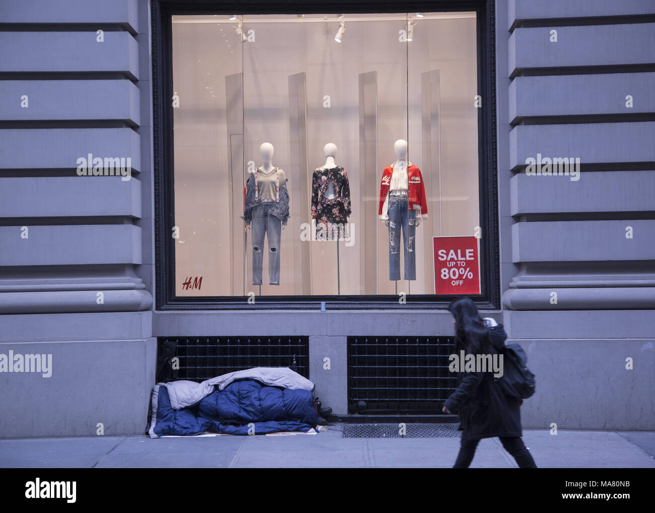 Obdachlose sleeper vor einem H&M Store display Fenster im Stadtteil Chelsea in Manhattan, New York City. Stockfoto