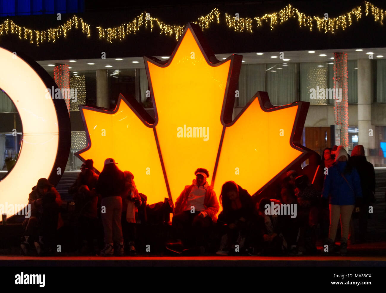TORONTO, KANADA - 2018-01-01: torontonians vor der glühenden Maple Leaf, der kanadische Symbol, Rest nach Spaß auf der Eislaufbahn Stockfoto TORONTO, KANADA - 2018-01-01: torontonians vor der glühenden Maple Leaf, der kanadische Symbol, Rest nach Spaß auf der Eislaufbahn Stockfoto