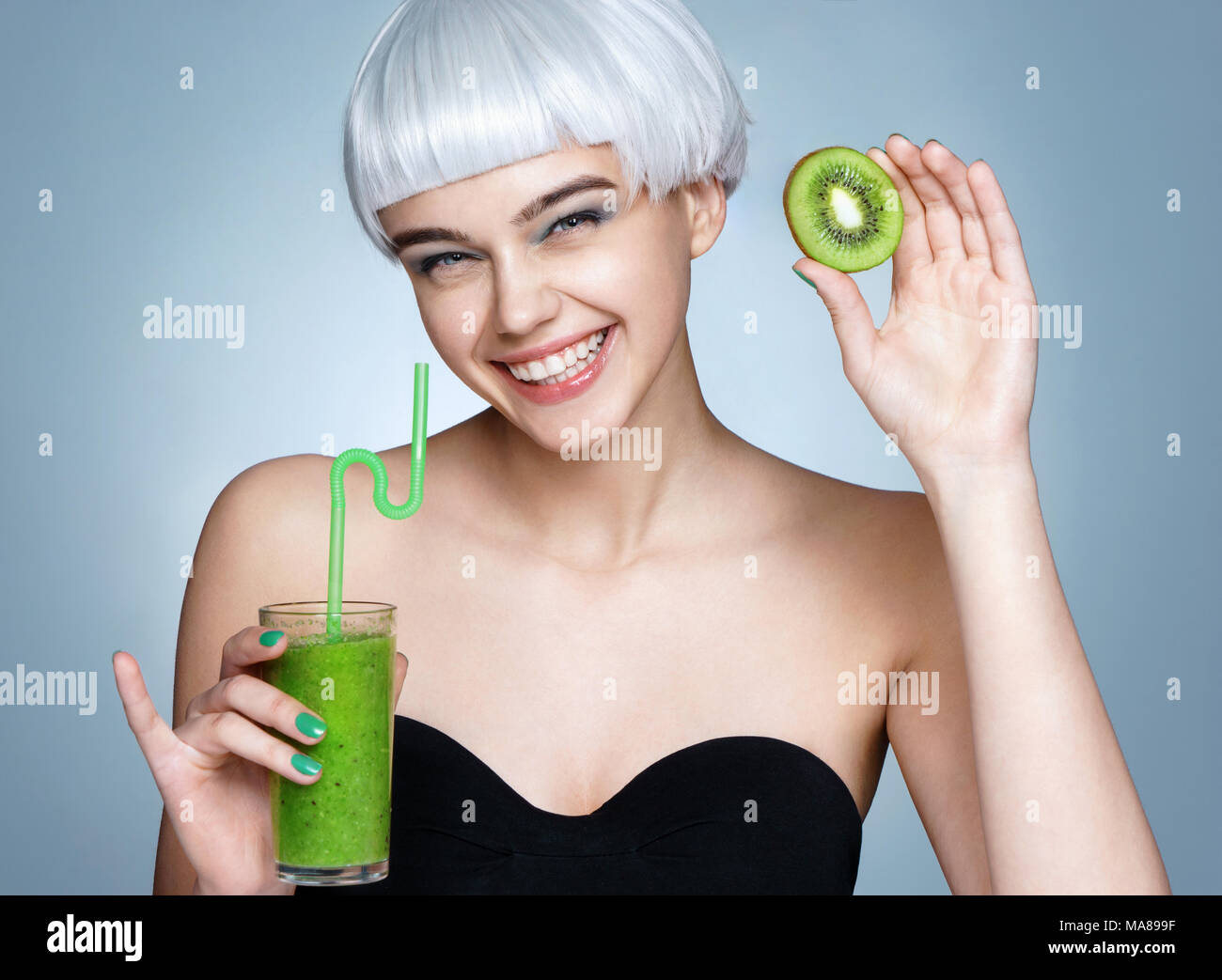 Lächelnden jungen Mädchen, dass Smoothie detox Cocktail der Kiwi. Foto, fashion model auf blauem Hintergrund. Gesunder Lebensstil Stockfoto