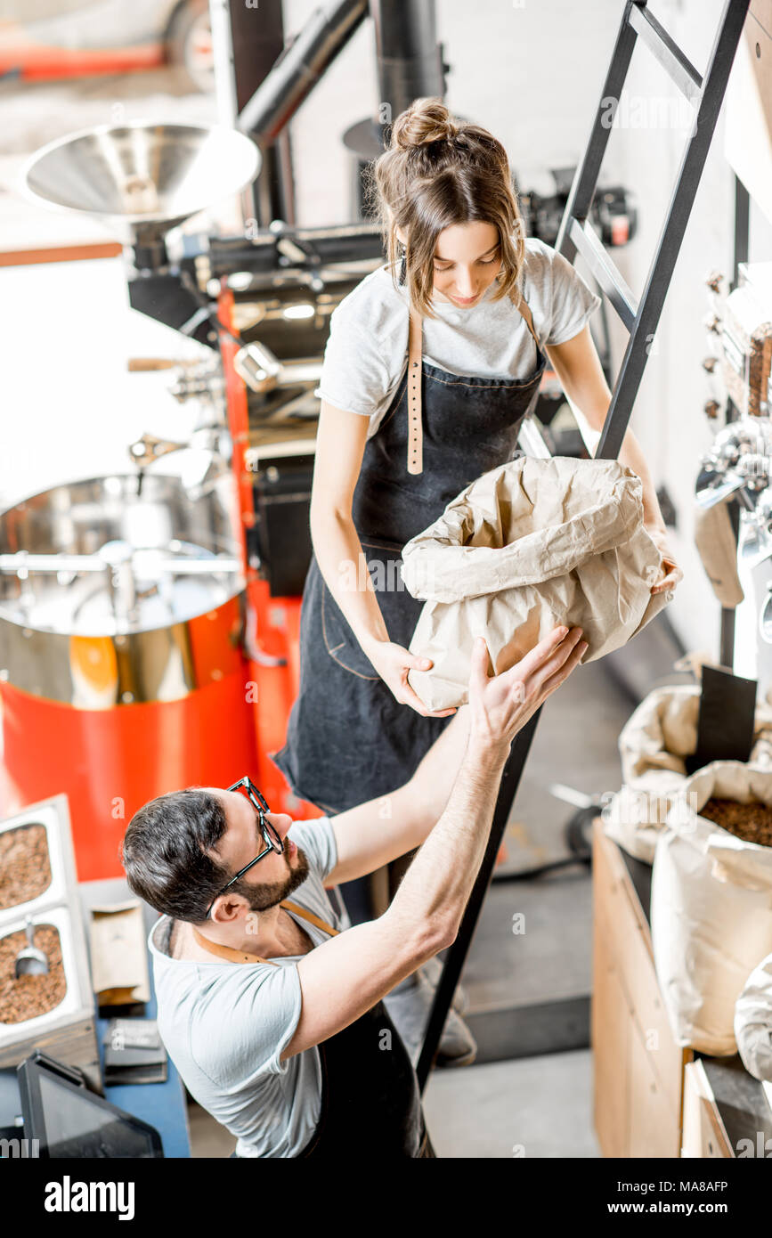 Zwei Personen arbeiten mit Kaffee im Café mit röster Maschine im Hintergrund Stockfoto
