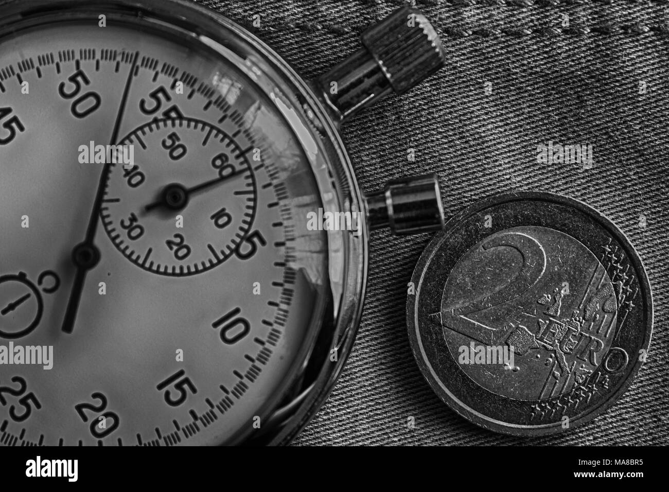 Euro Münze mit einer Stückelung von 2 Euro und die Stoppuhr auf abgenutzten denim Kulisse - Geschäft Hintergrund. Stockfoto