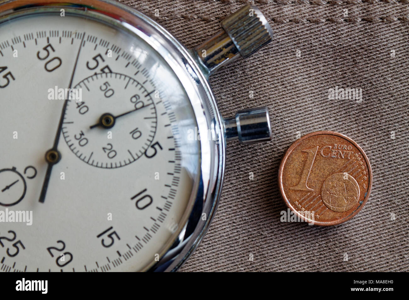 Euro Münze mit einer Stückelung von 1 Euro Cent und die Stoppuhr auf abgenutzten beige denim Hintergrund - Hintergrund Stockfoto