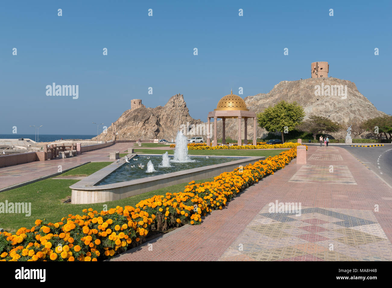 Uferpromenade am Riyam, Mutrah (alten) Muscat im Oman mit alten Wachtürme auf den Felsvorsprüngen (ein jetzt verwendet zur Unterbringung von TK-Einrichtungen) Stockfoto