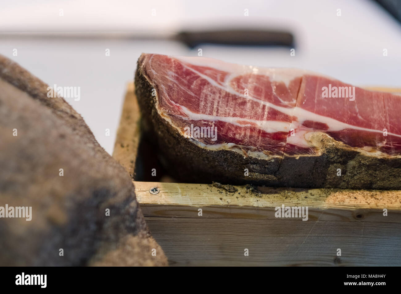 Exklusive italienische Prosciutto, kuriert Schweinefleisch in einer Holzkiste mit Messer im Hintergrund Stockfoto
