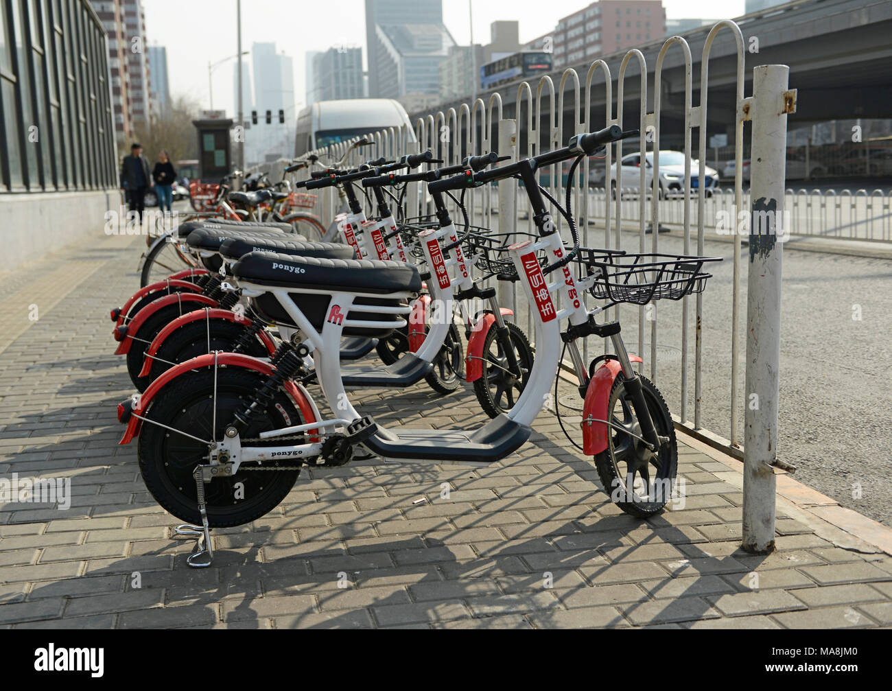 Dockless elektrische Fahrräder zum Mieten durch eine Kreuzung auf der dritten Ringstraße in Tuanjiehu in Peking, China geparkt Stockfoto
