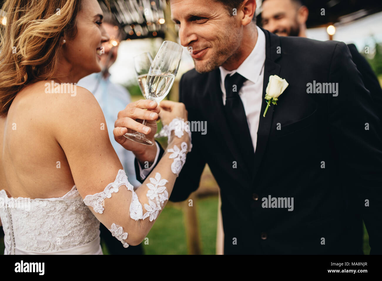 Brautpaar anstoßen und romantische Moment zusammen bei Hochzeit außerhalb. Braut und Bräutigam trinken Champagner in der Hochzeitsgesellschaft. Stockfoto