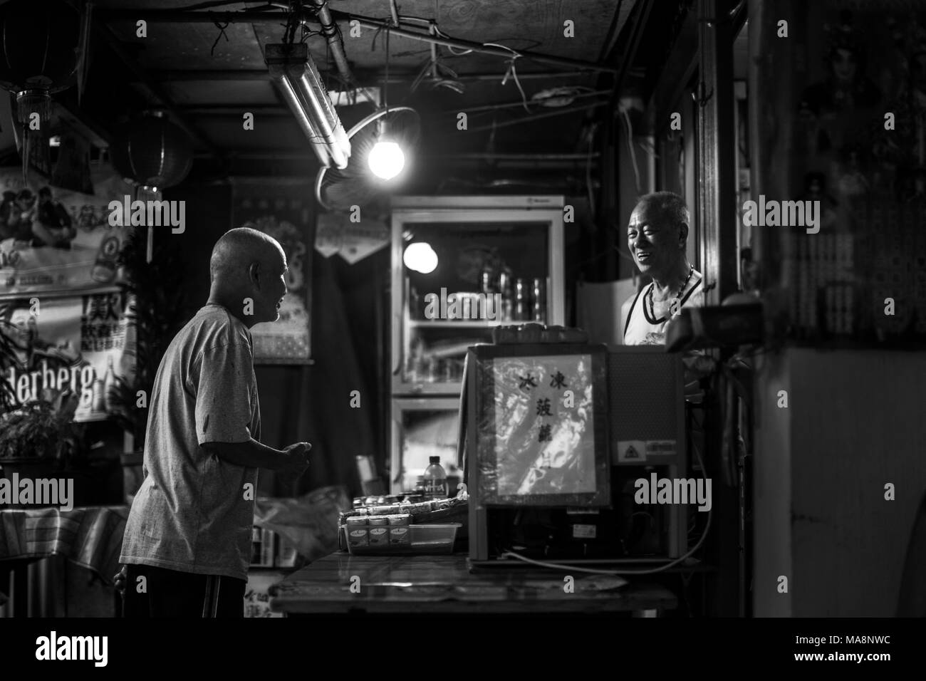 Zwei Männer sprechen in den frühen Abend bei einem Shop in das Fischerdorf Tai O, Hong Kong Stockfoto
