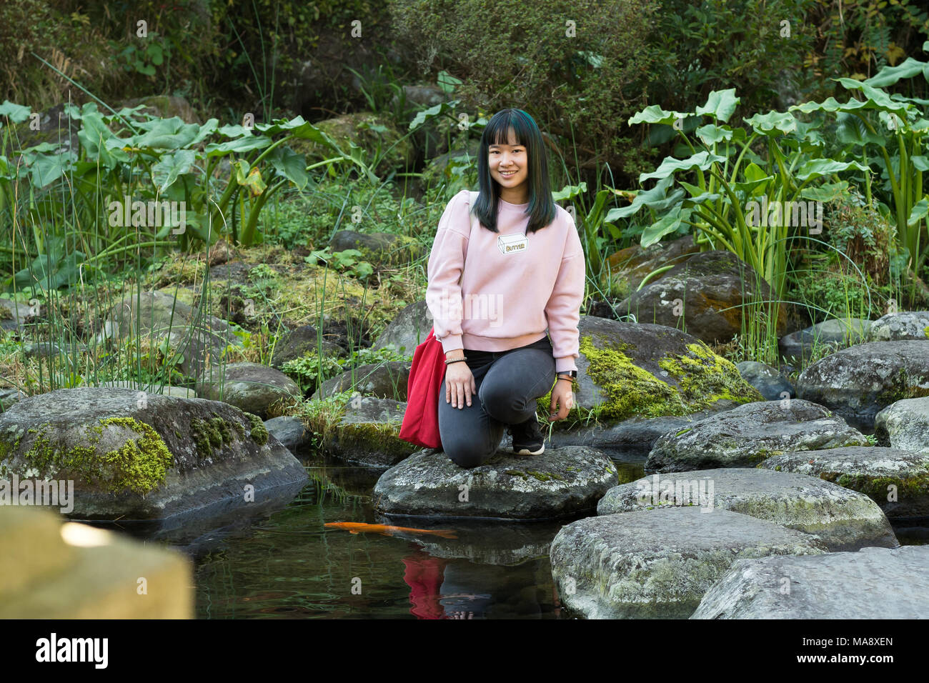 Junge Asiatin in einem japanischen Garten in der Nähe von einem Teich fischen Posing Stockfoto