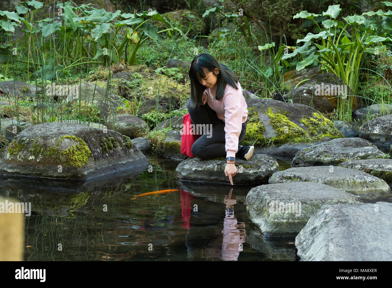 Junge Asiatin in einem japanischen Garten in der Nähe von einem Teich fischen Posing Stockfoto