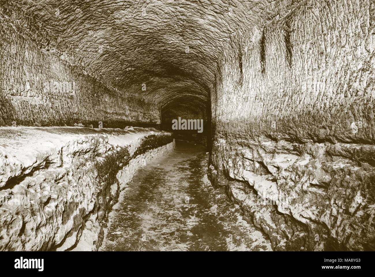 Die alte Sandstein Tunnel, Höhlen abgebaut. Die Höhle. Sandstein Tunnel feuchten Wänden. Trockene Kanal in den felsigen Untergrund geschnitzt. Solarisation Wirkung Stockfoto