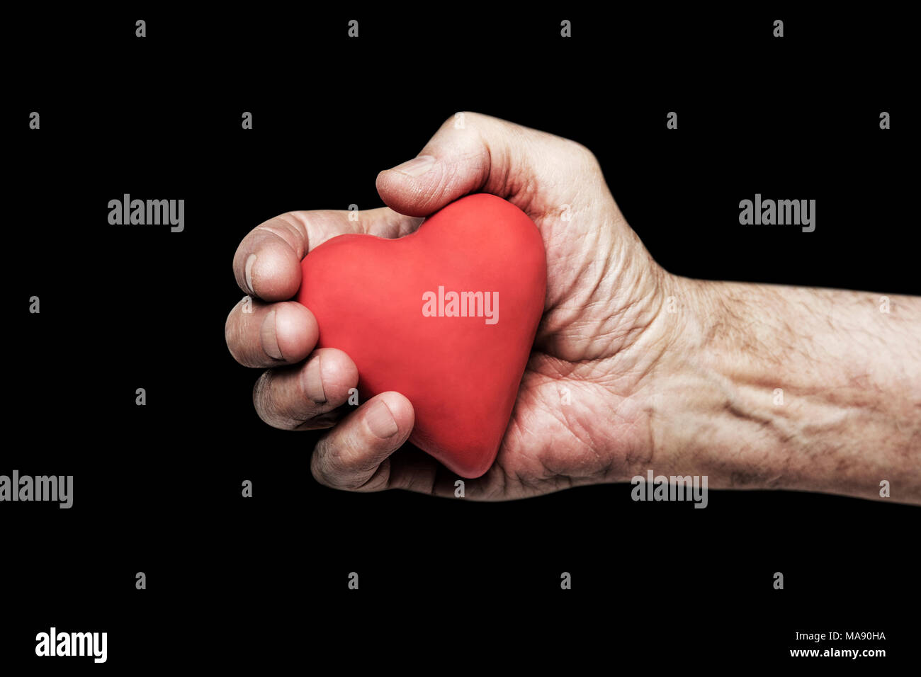 Rotes Herz in der Hand vor schwarzem Hintergrund Stockfoto
