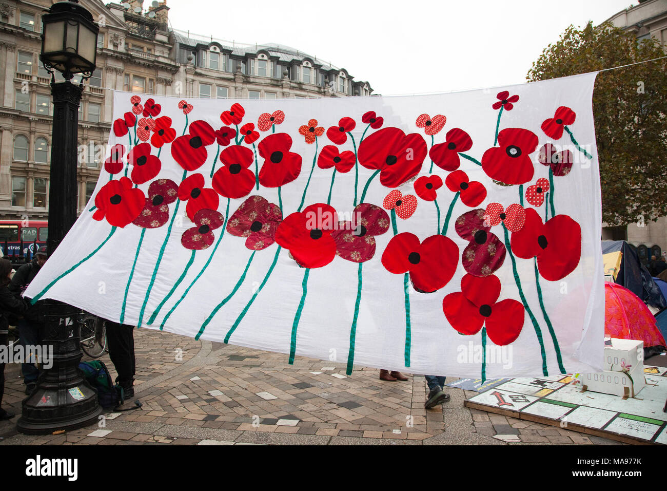 Ein großes, weißes Banner mit roter Mohn konnte an der London camp Belegen an die St Paul's Kathedrale gesehen werden. Stockfoto