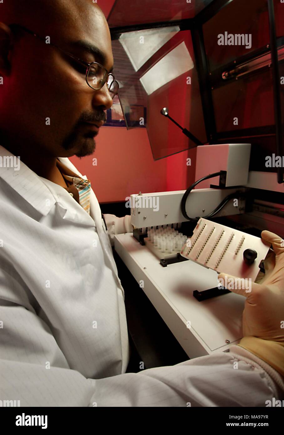 Nahaufnahme Foto des CDC Biologe und ein NCHHSTP Mitarbeiter Damian Danavall, in einem Labor, das Vorbereiten einer Maschine für die Handhabung von Flüssigkeiten, für den Zweck der Durchführung einer PCR-Test für die Replikation der DNA und RNA molekulare Sequenzen für den Nachweis von Herpes Simplex Virus 2, 2007. Mit freundlicher CDC/Hsi Liu, James Gathany. () Stockfoto