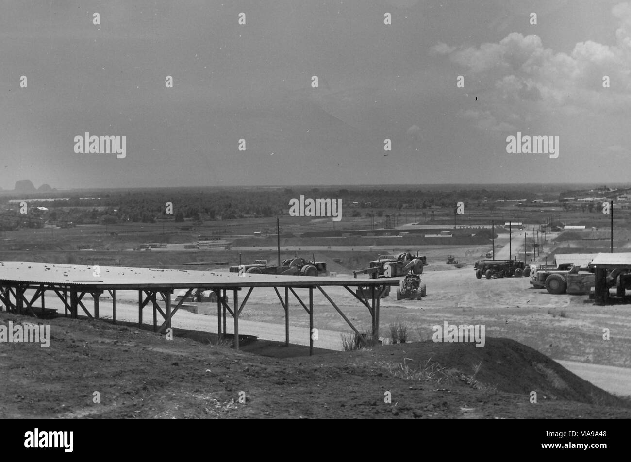 Schwarz-weiß Foto zeigt einen Blick auf den mit Gras bewachsenen Ebenen oder Felder, die mit einem Ramada oder offenen Schuppen und verschiedene militärische Fahrzeuge in den Vordergrund, die in Vietnam während des Vietnam Krieges, 1971 fotografiert. () Stockfoto