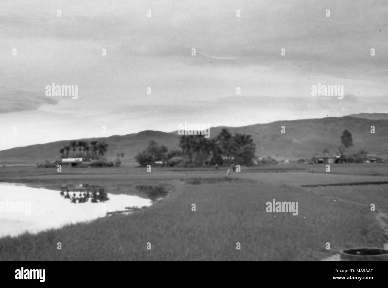 Schwarz-weiß Foto zeigt eine Landschaft, mit einem See und Reisfelder im Vordergrund, Häuser und Bäume im Mittelgrund und einem Hügel im Hintergrund, die in Vietnam während des Vietnam Krieges fotografiert (1955-1975), 1968. () Stockfoto