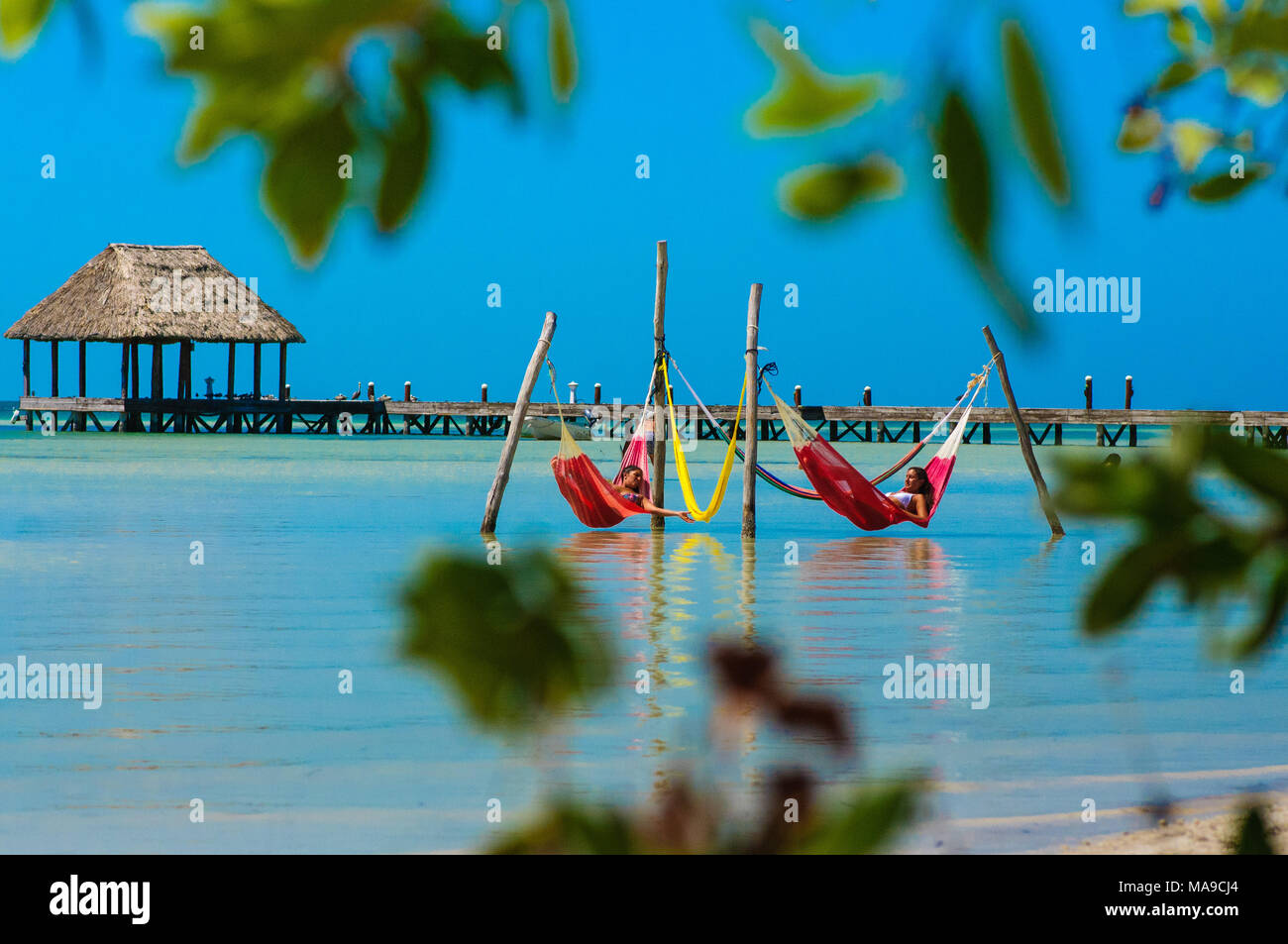 Menschen entspannen in einem roten Hängematten über das Karibische Meer am Strand in Holbox, Mexiko Stockfoto
