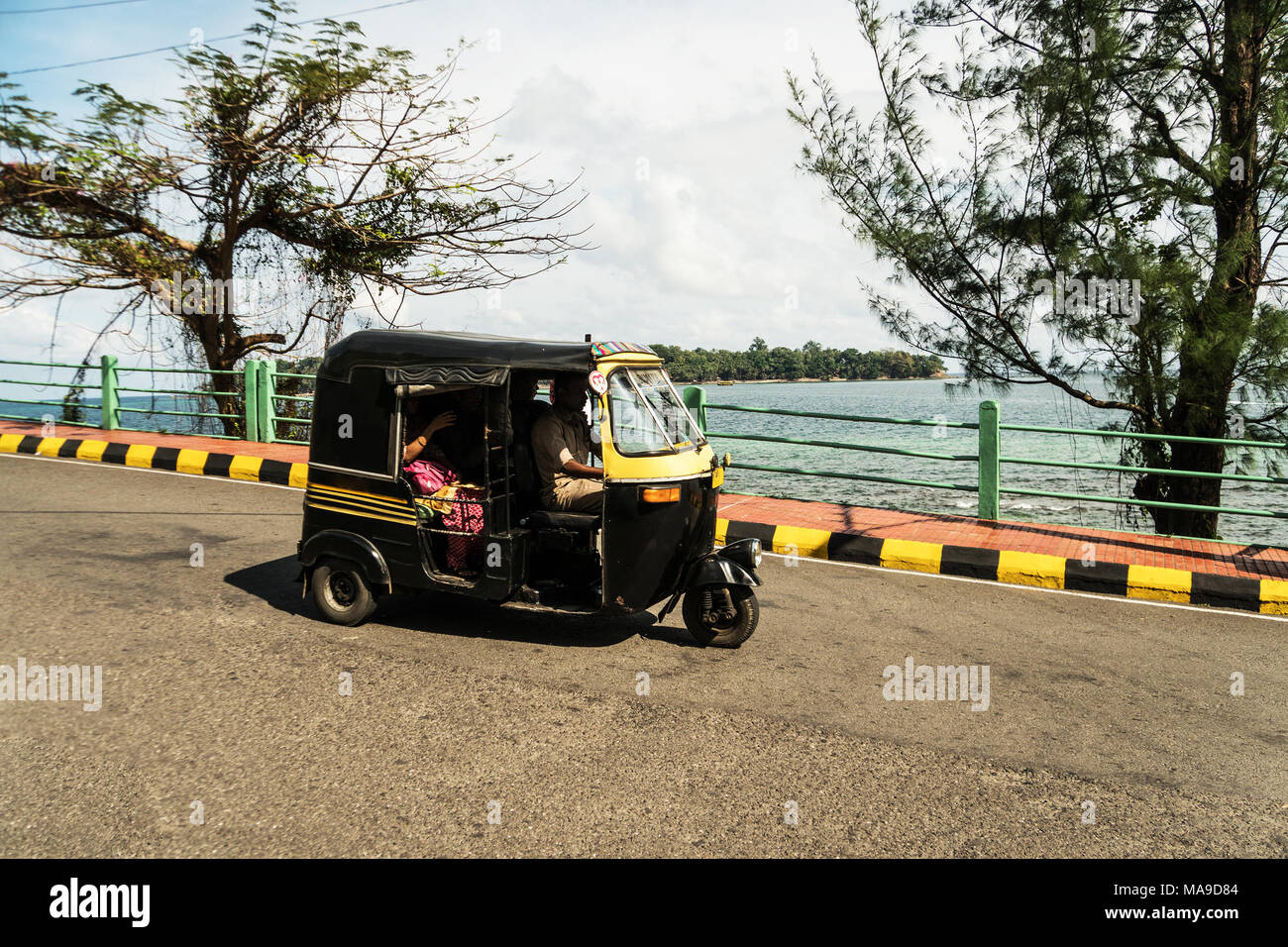 Tuk Tuk Passagiere auf der Straße gegen das Meer. Andaman und Nicobar Inseln, Port Blair. Indien. Januar 12, 2018 Stockfoto