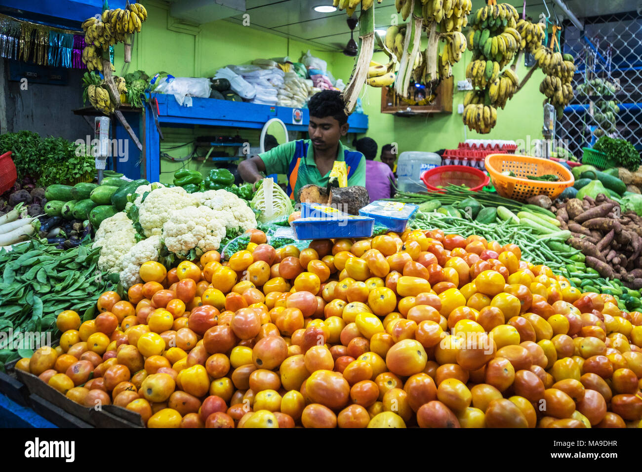 Ein Inder verkauft Gemüse und Früchte in seiner Straße Shop. Frische Tomaten im Vordergrund. Indien Goa. 12. Januar 2018 Stockfoto